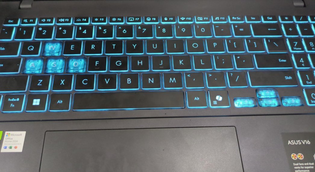 ASUS V16 laptop keyboard with cyan backlight and highlighted WASD keys