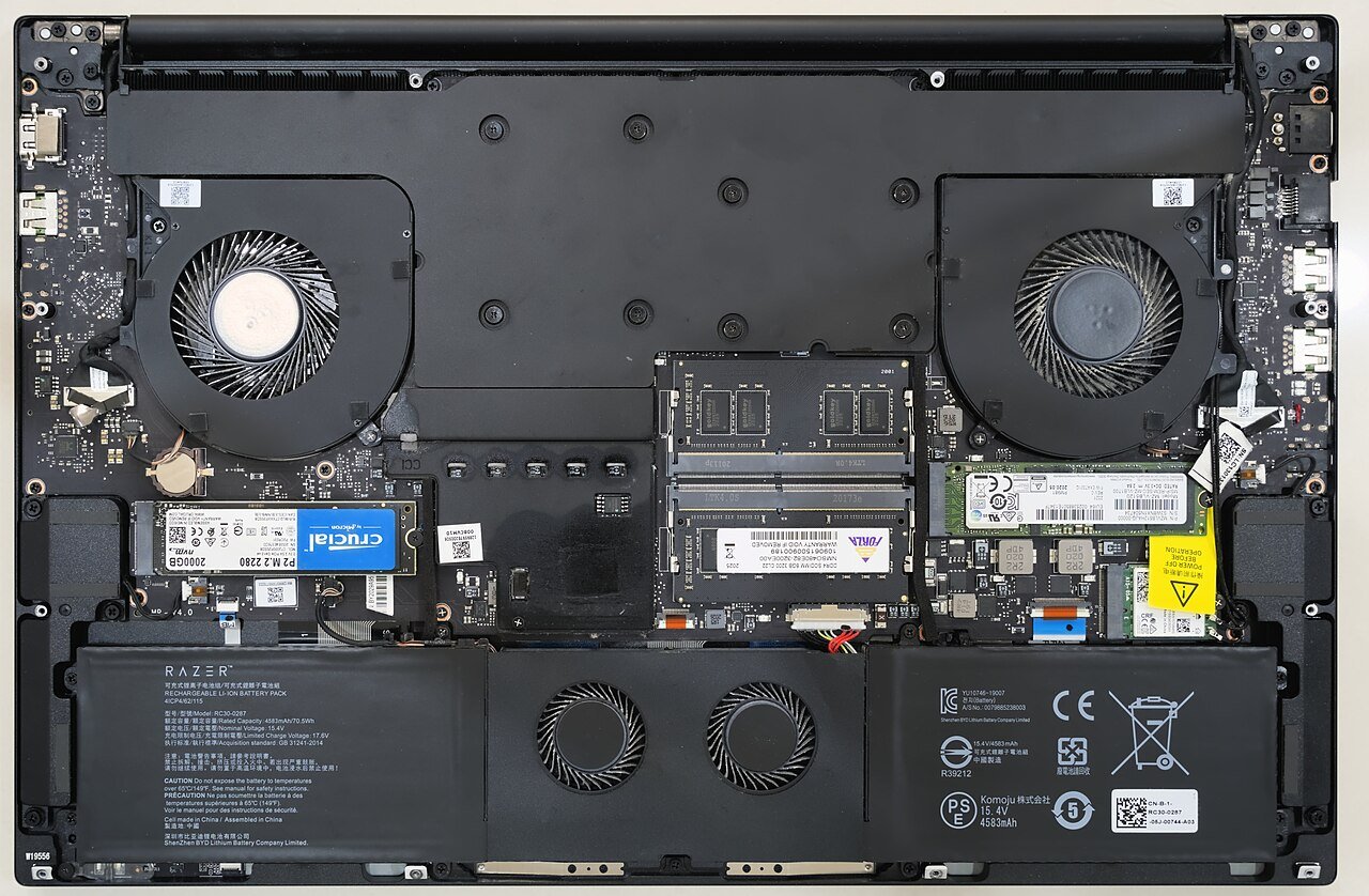 Gaming laptop with the bottom panel removed showing RAM, SSD, fans and battery