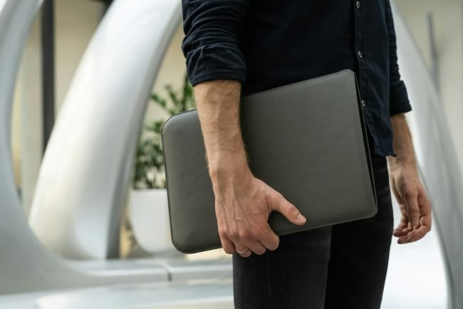 Man carrying a laptop in a sleeve with one hand