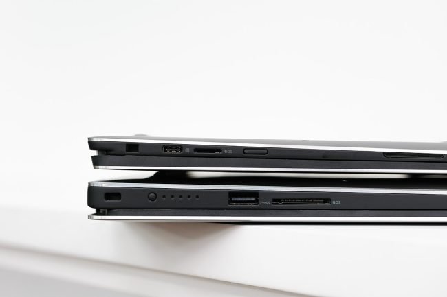 Two Dell XPS laptops stacked, side view showing thickness and ports