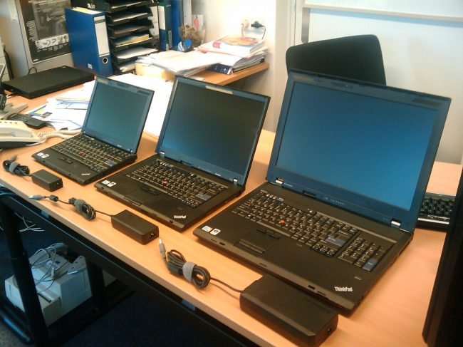 Three Lenovo ThinkPad laptops in different screen sizes on an office desk